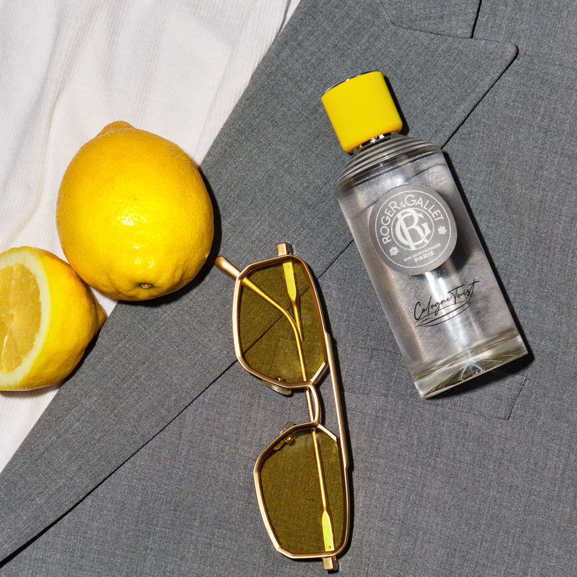 Flacon d'eau de Cologne avec bouchon jaune, lunettes de soleil et citron. Inscription : Roger & Gallet, Cologne Twist.