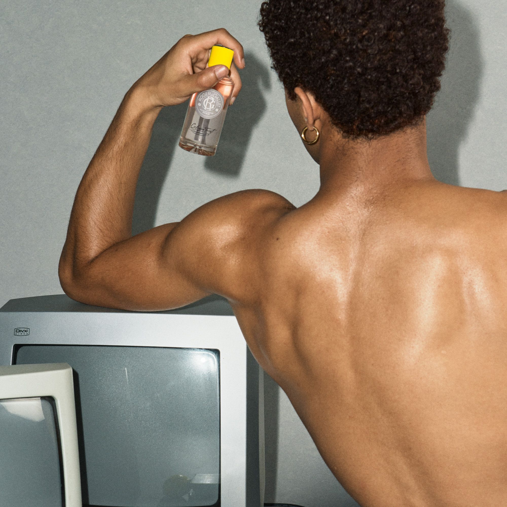 Man met flesje eau de cologne. Opschrift: Roger & Gallet, Cologne Twist.