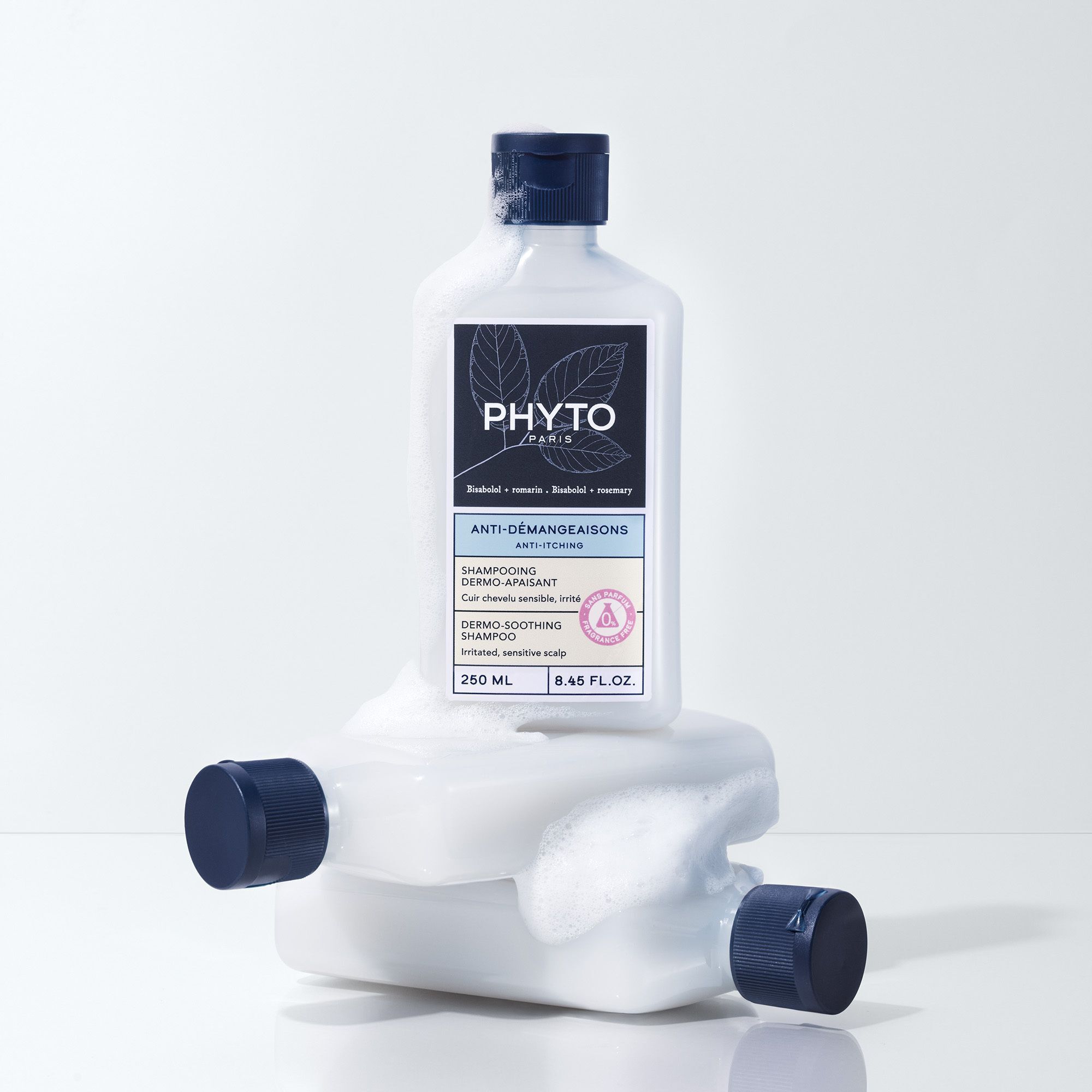 Fles Phyto Anti-Démangeaisons shampoo. Witte fles met blauwe dop op twee andere flessen. Tekst: Anti-jeuk, Dermo-verzachtend.