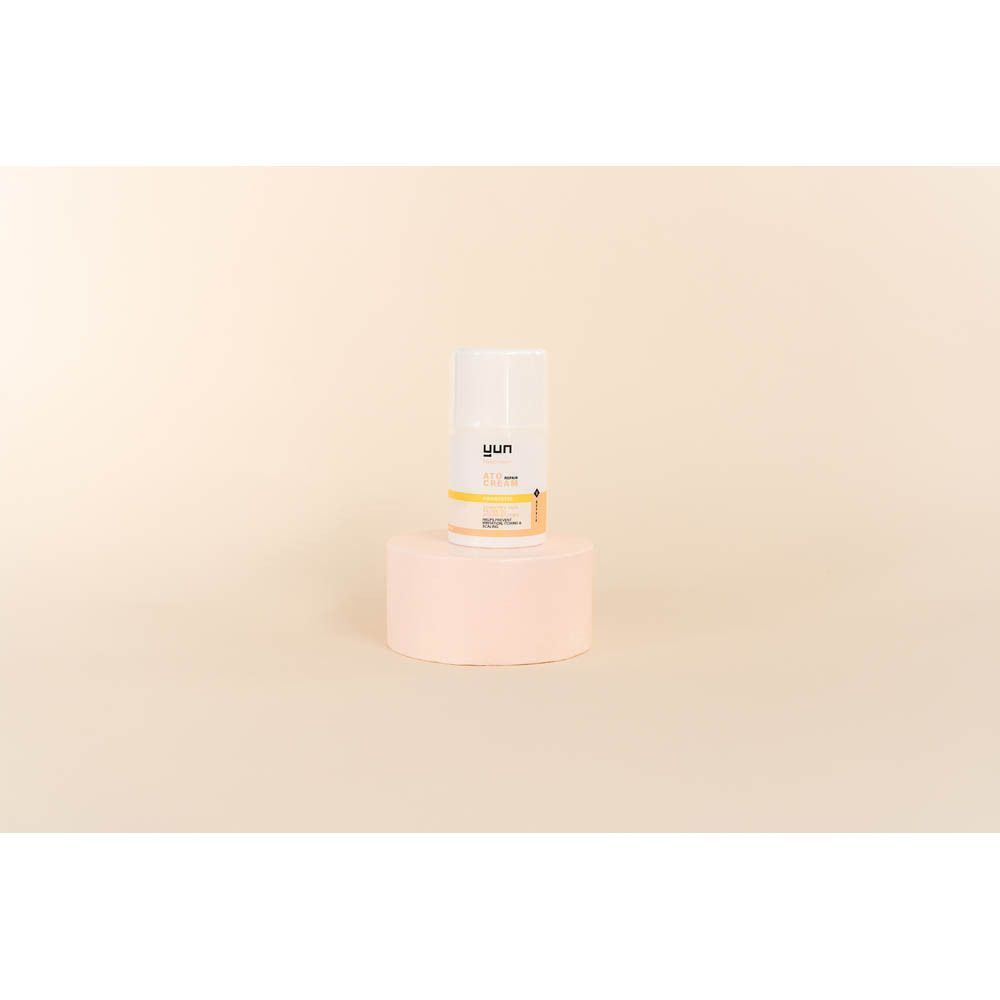 Kleine witte fles met gele en roze accenten. Op een roze sokkel. YUN ATO.