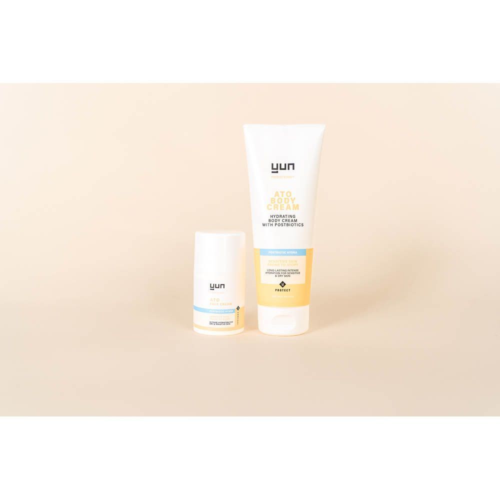 Deux produits: un tube et un petit flacon. Tous deux blancs avec des accents jaunes et bleus. YUN ATO.