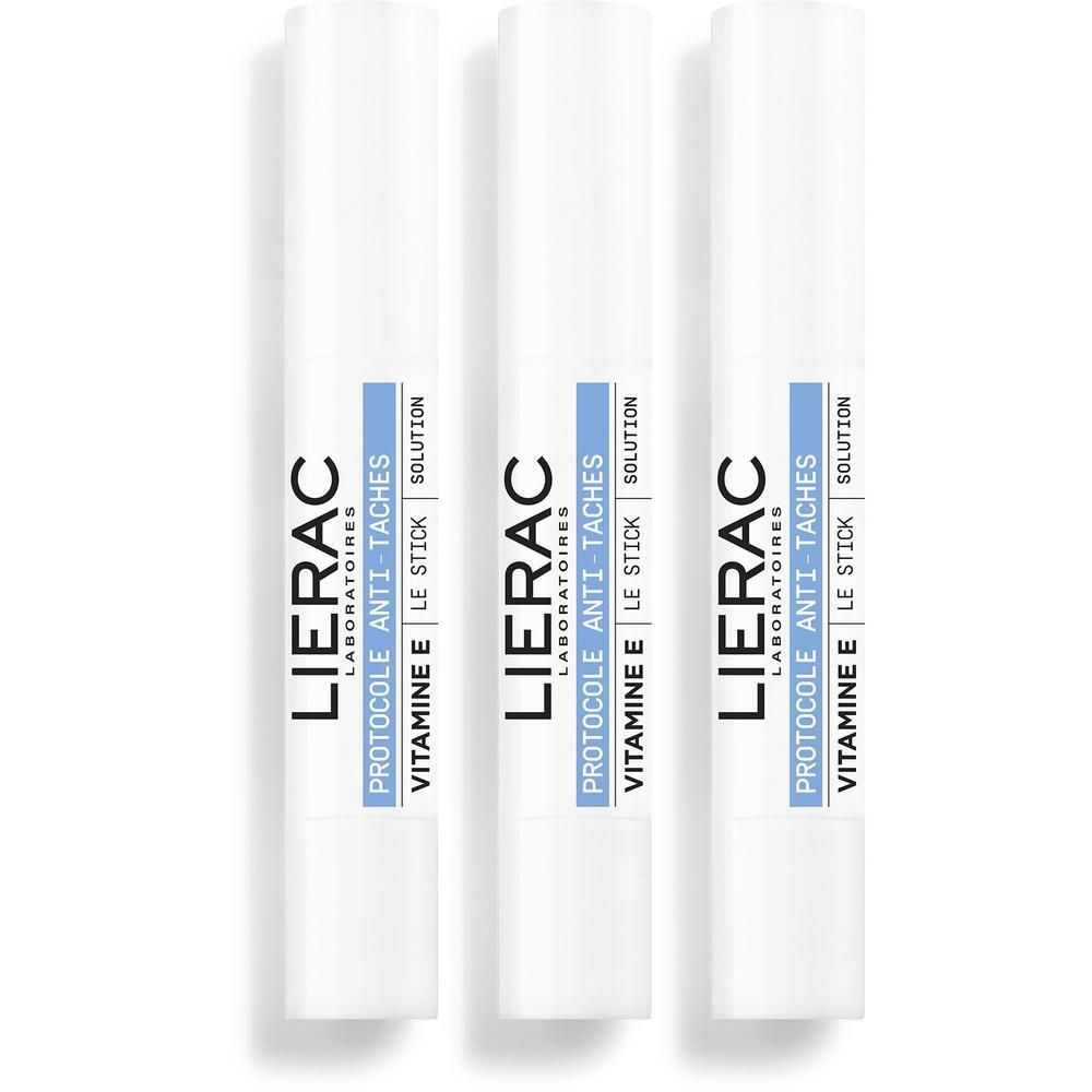 Trois sticks blancs avec étiquette bleue. Inscription: Lierac, Protocole Anti-Taches, Vitamine E, Le Stick Solution.