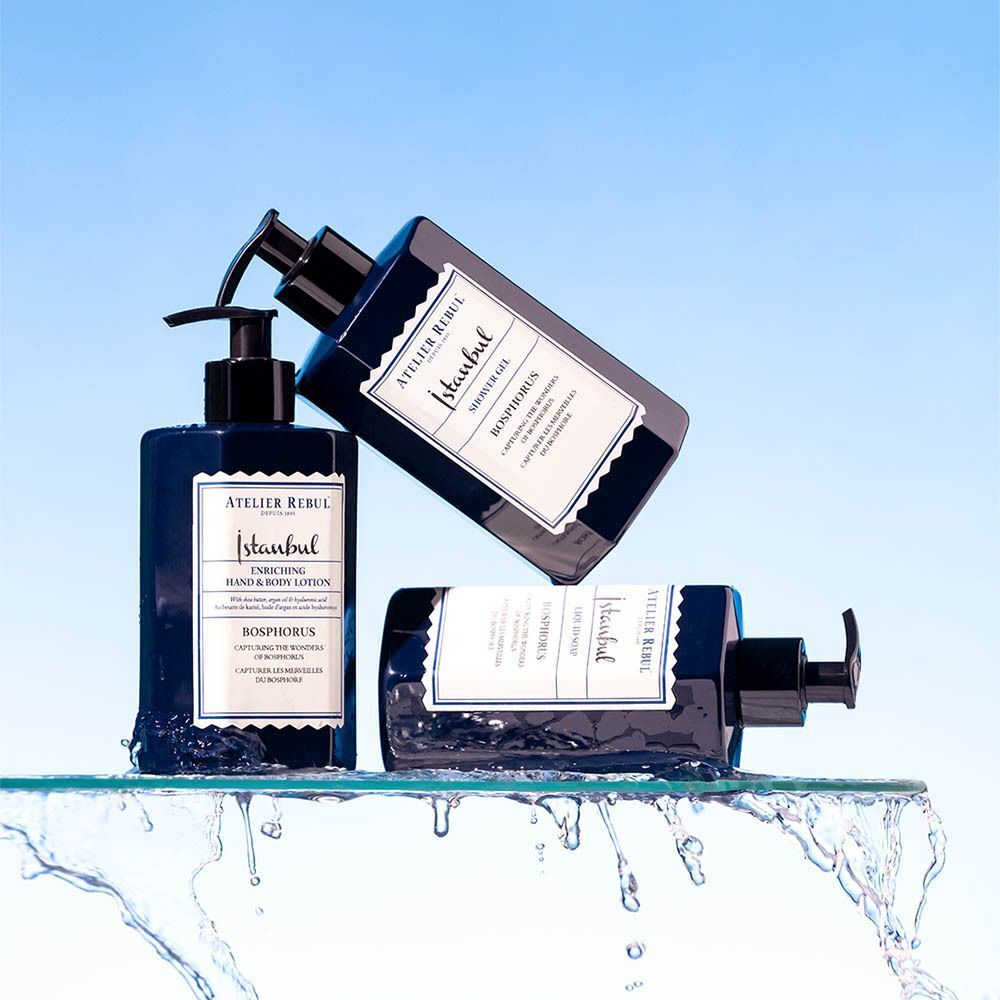 Trois lotions bleues avec pompes noires. Étiquettes avec texte. Sur verre, éclaboussures d'eau.