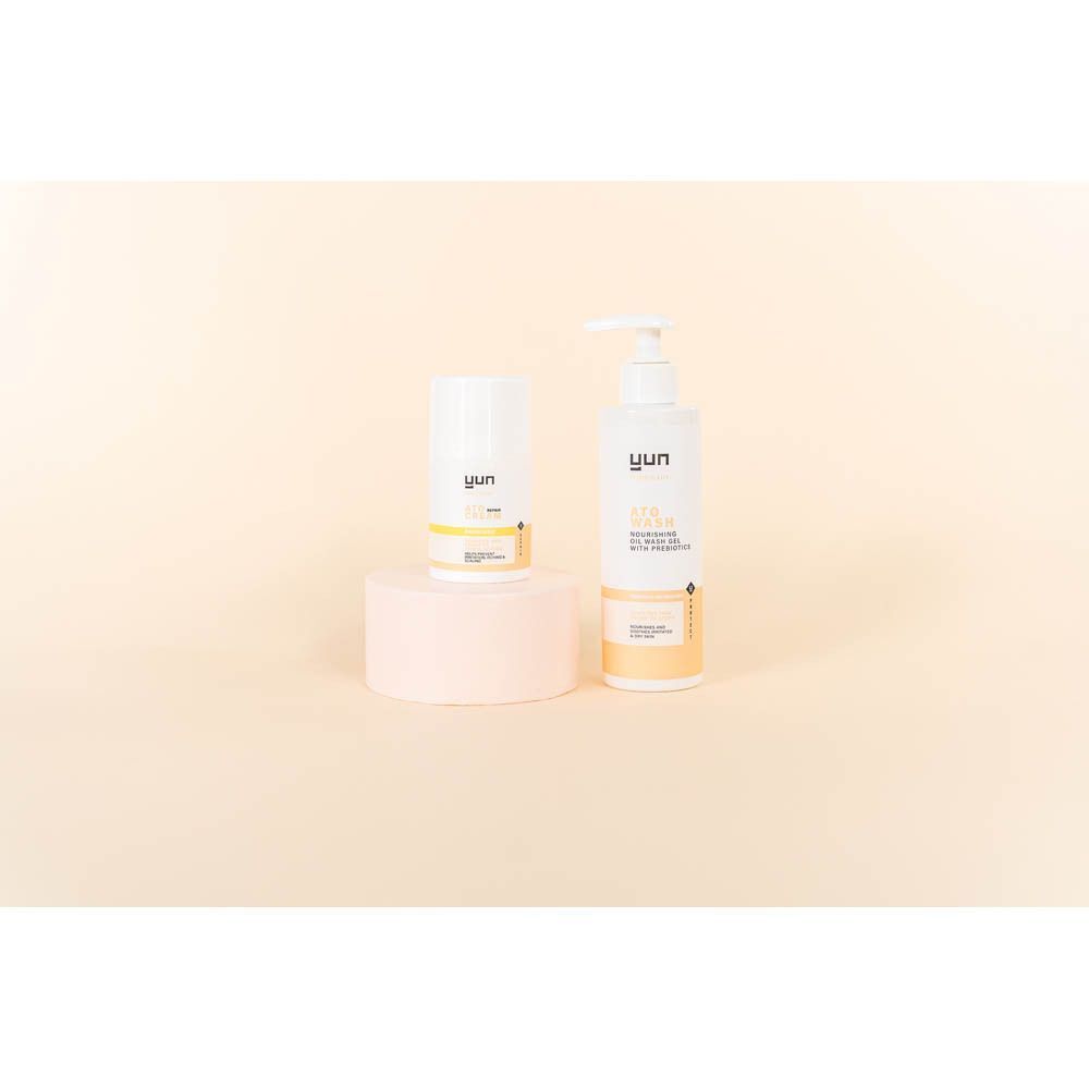 Een witte fles en tube op een roze sokkel. Opschrift: YUN ATO WASH en ATO CREAM. Beige achtergrond.