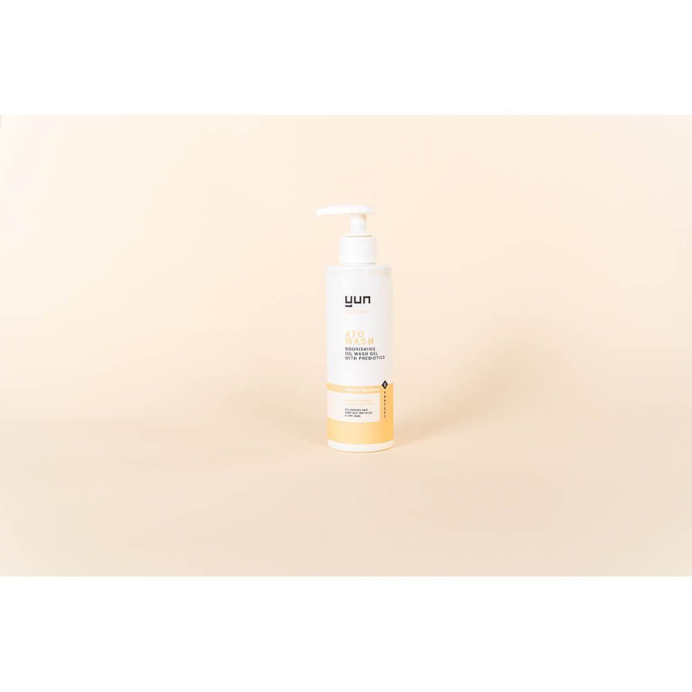 Een witte fles met pomp. Opschrift: YUN ATO WASH. Beige achtergrond.