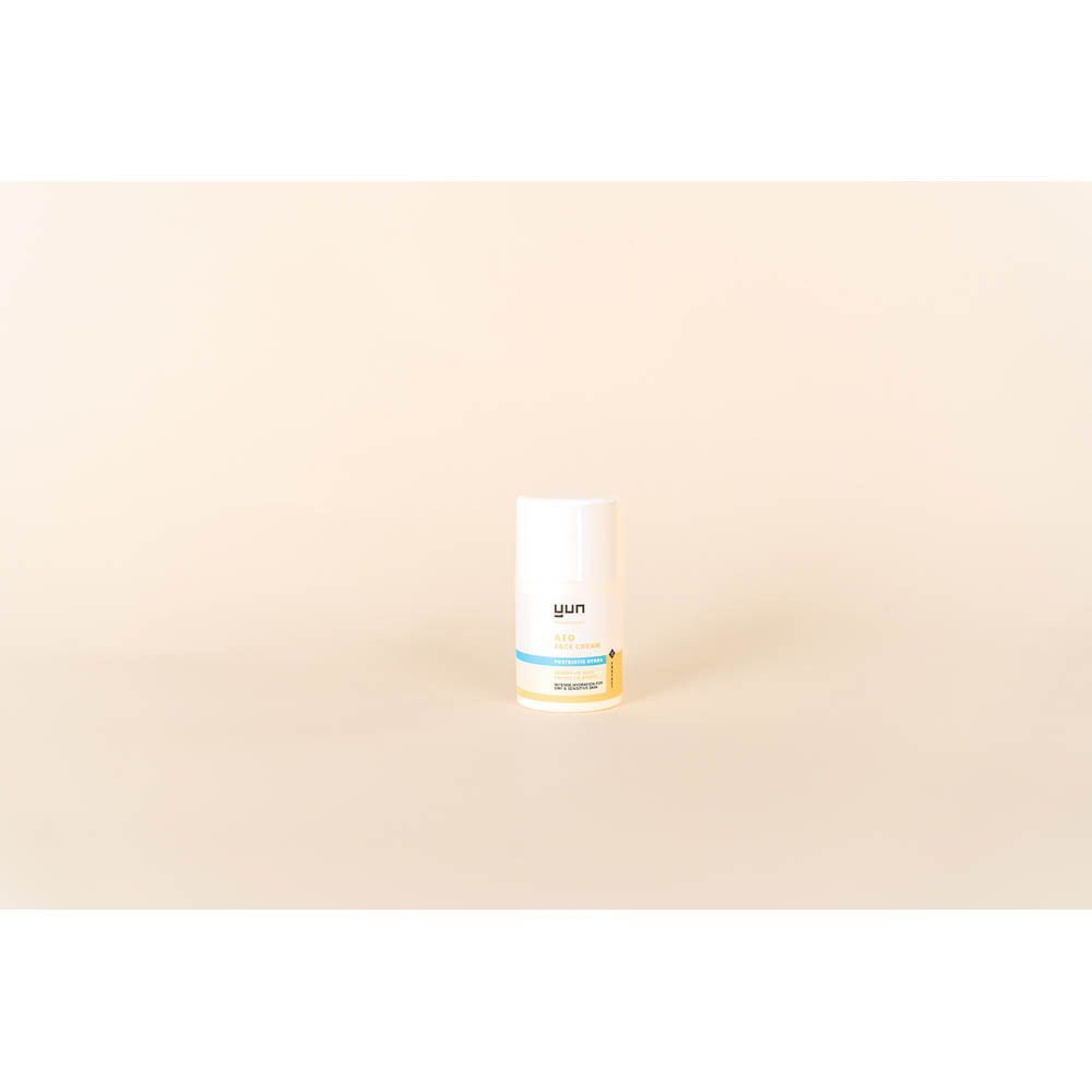 Een witte tube. Opschrift: YUN ATO CREAM. Gele en blauwe streep. Beige achtergrond.