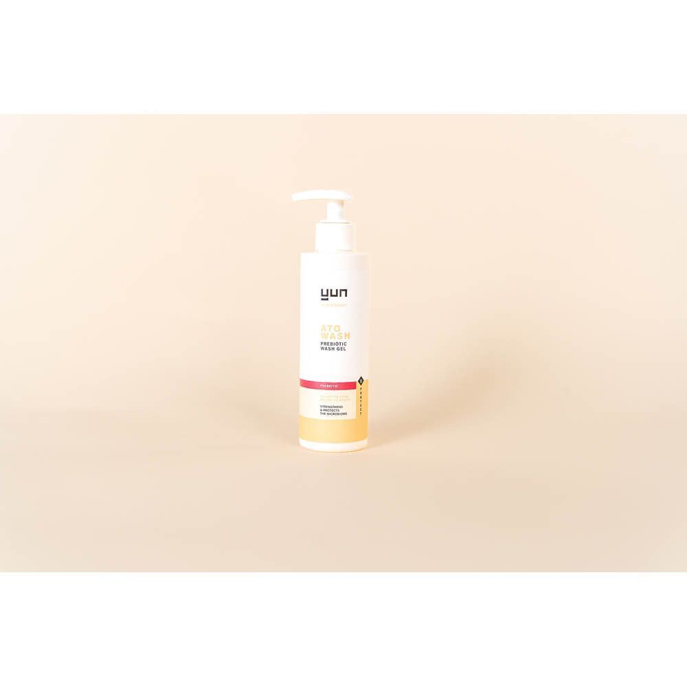 Een witte fles met pomp. Opschrift: YUN ATO WASH. Beige achtergrond.