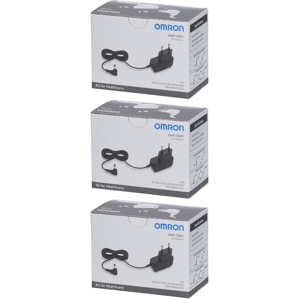 Trois adaptateurs OMRON HHP-CM01 dans des boîtes. Adaptateurs noirs avec câbles. Inscription : OMRON, All for Healthcare.