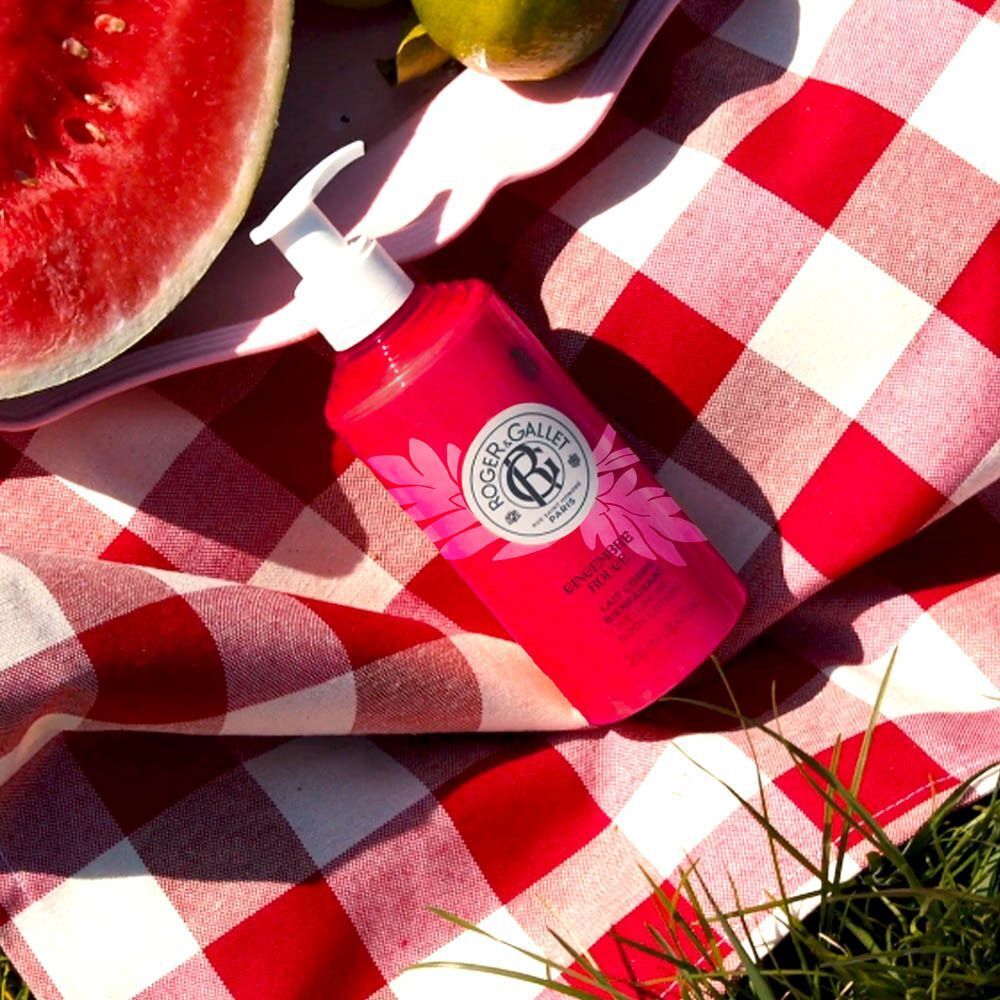 Rode fles met witte pomp op een rood-wit geruite picknickdeken. Watermeloen en fruit.