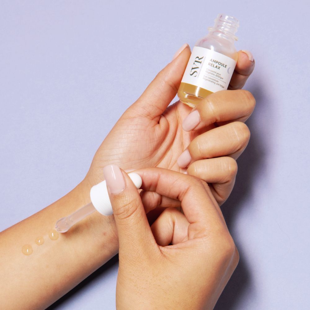 Persoon druppelt vloeistof uit een pipet op haar arm. Flesje met "SVR Ampoule Relax".