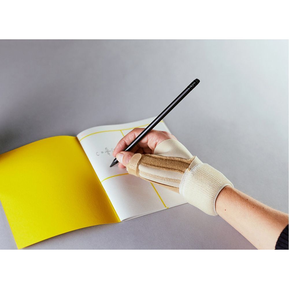 Persoon schrijft met een pen, draagt een FUTURO™ duimbrace. Beige, bevestigd aan de pols.