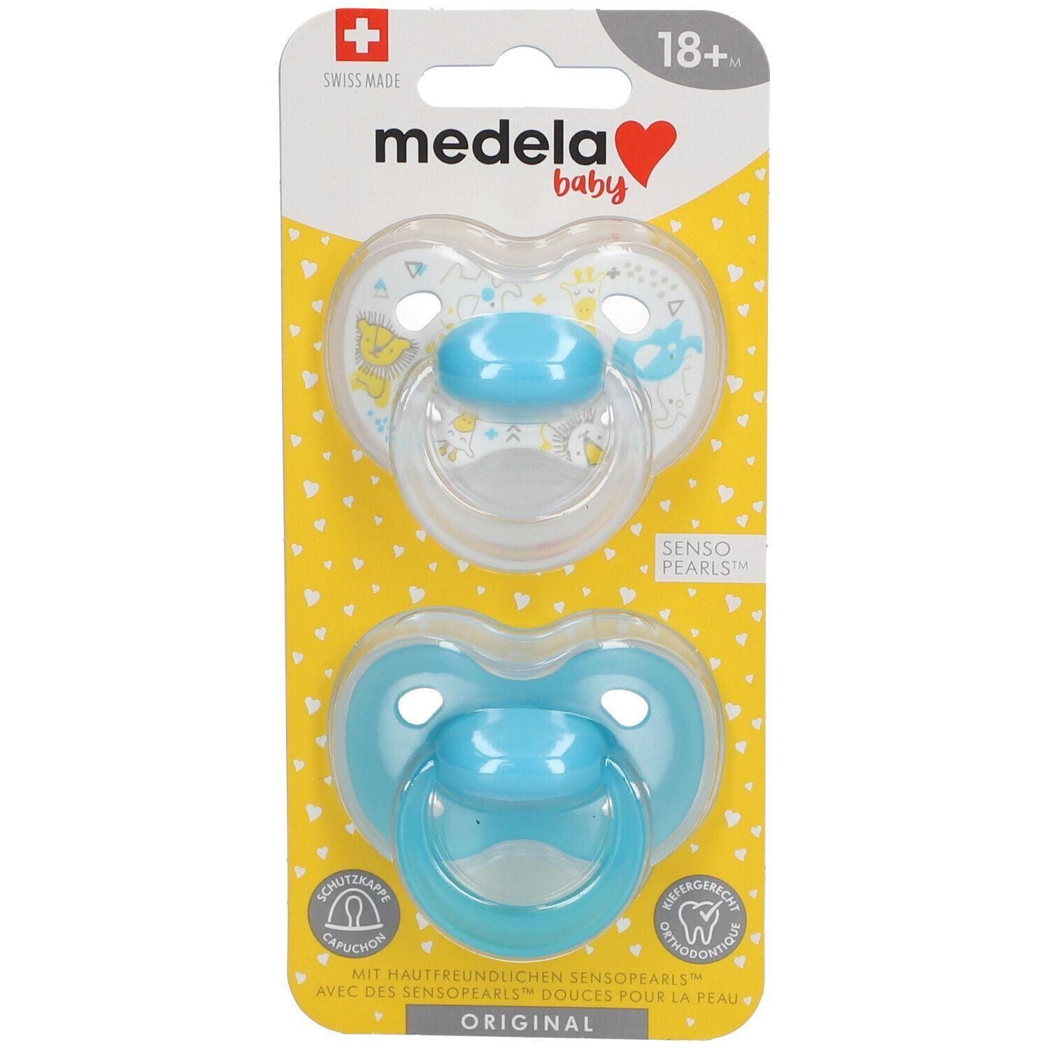 Deux sucettes Medela Baby, bleu et transparent, emballées. Recommandé pour les 18 mois et plus. Avec Senso Pearls.