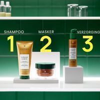Gouden fles shampoo, groen potje masker, bruine fles met pomp voor haarverzorging.