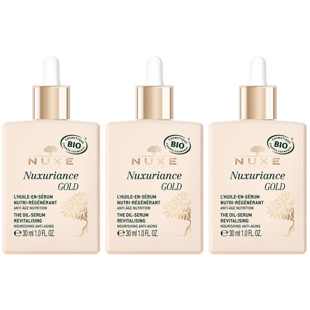 Drie flacons Nuxe Nuxuriance Gold olie-serum. Vierkante beige vorm, gouden dop en pipet. Opschrift en bio-label.