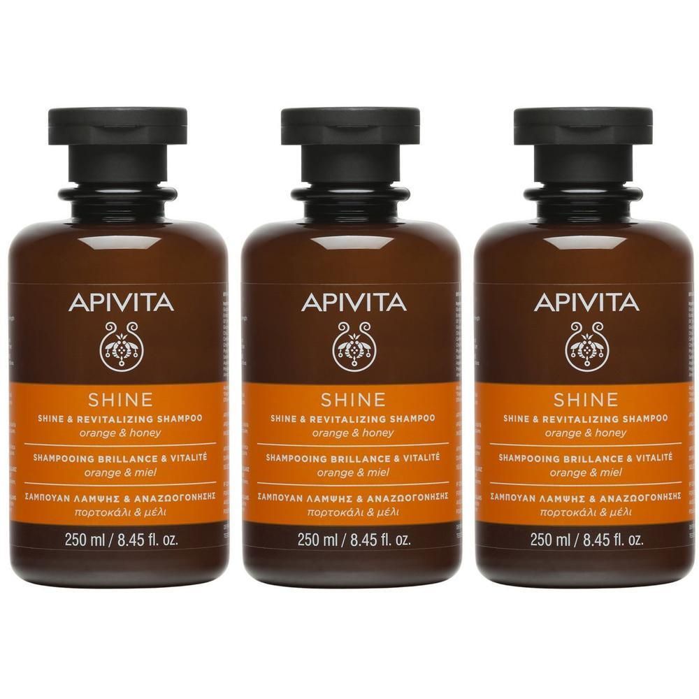 Trois flacons de shampooing Apivita Shine Brillance & Vitalité. Flacons bruns avec bouchon noir. Inscription: SHINE, orange & miel.