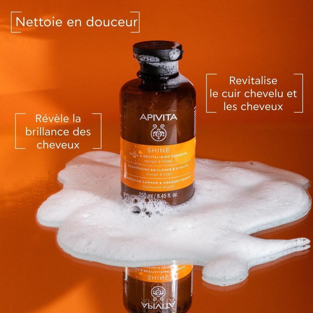 Flacon de shampooing Apivita Shine Brillance & Vitalité sur mousse. Texte: Nettoie en douceur, Révèle la brillance des cheveux, Revitalise le cuir chevelu.