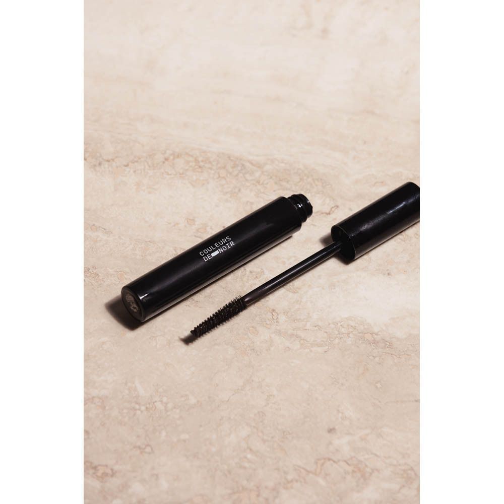 Tube de mascara noir et brosse sur fond beige. Le texte "COULEURS DE NOIR" est visible sur le tube.