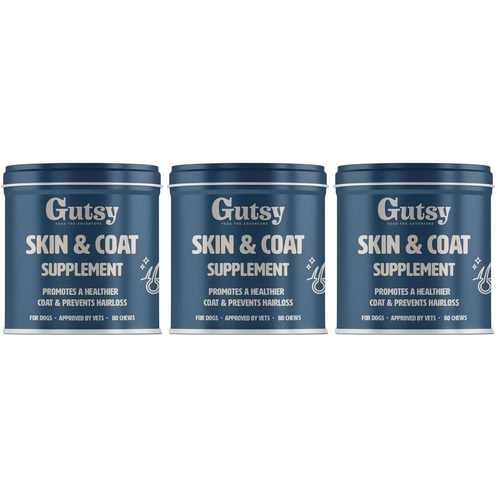 Drie blauwe blikken met de tekst "Gutsy SKIN & COAT SUPPLEMENT". Tekst: Bevordert een gezondere vacht en voorkomt haaruitval.