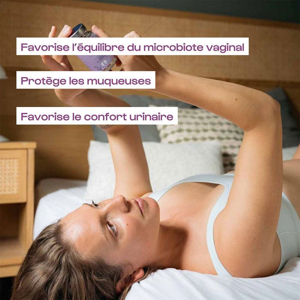 Femme allongée au lit tenant un flacon Omum L'intime. Texte : Favorise l'équilibre de la flore vaginale, protège les muqueuses.