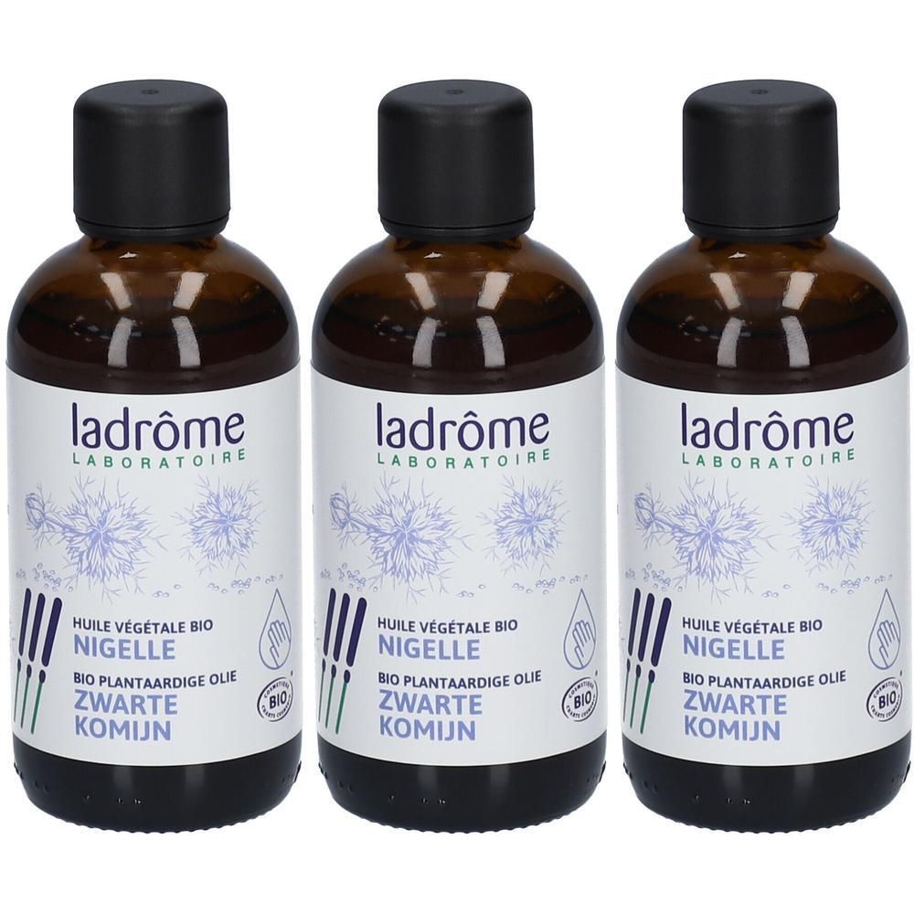 Drie bruine flessen met zwarte doppen. Labels met "ladrôme LABORATOIRE", "HUILE VEGETALE BIO NIGELLE" en "ZWARTE KOMIJN".