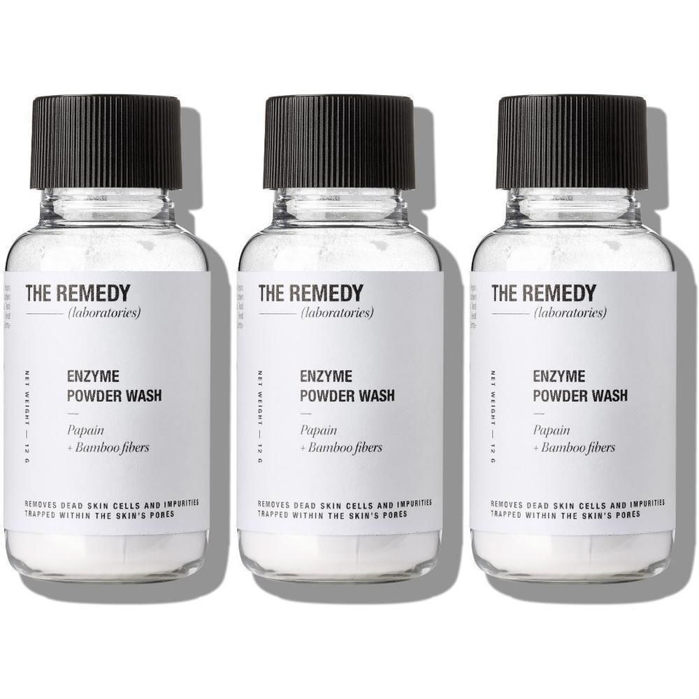 Drie flessen met zwarte doppen en witte etiketten. Op het etiket staat "THE REMEDY" en "ENZYME POWDER WASH".