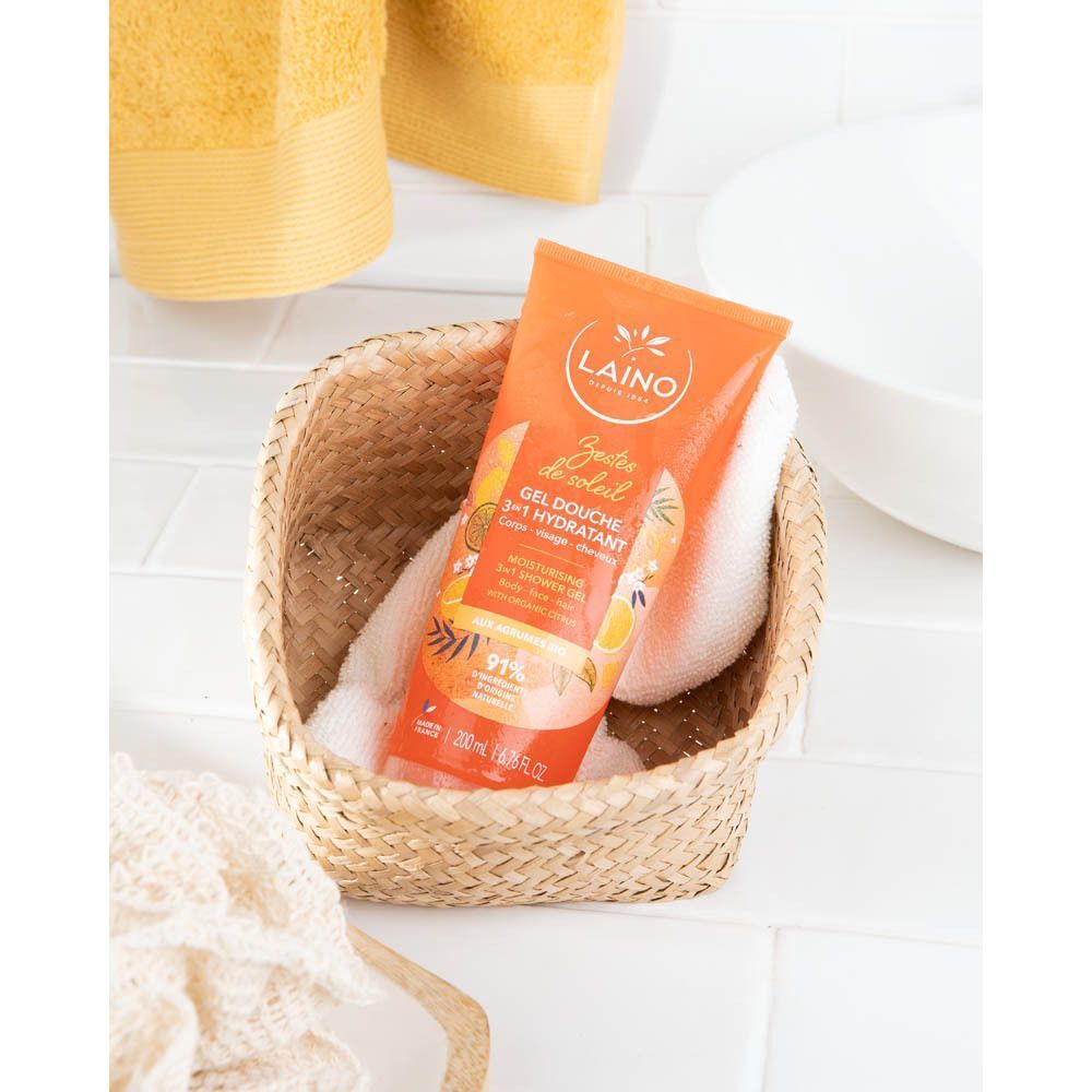 Tube de gel douche orange dans un panier tressé avec de la mousse. Serviettes en arrière-plan.