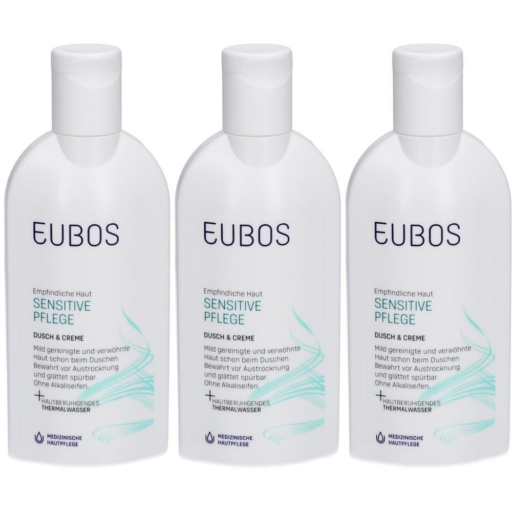 Trois flacons blancs EUBOS Sensitive Douche & Crème avec des lignes ondulées turquoise.
