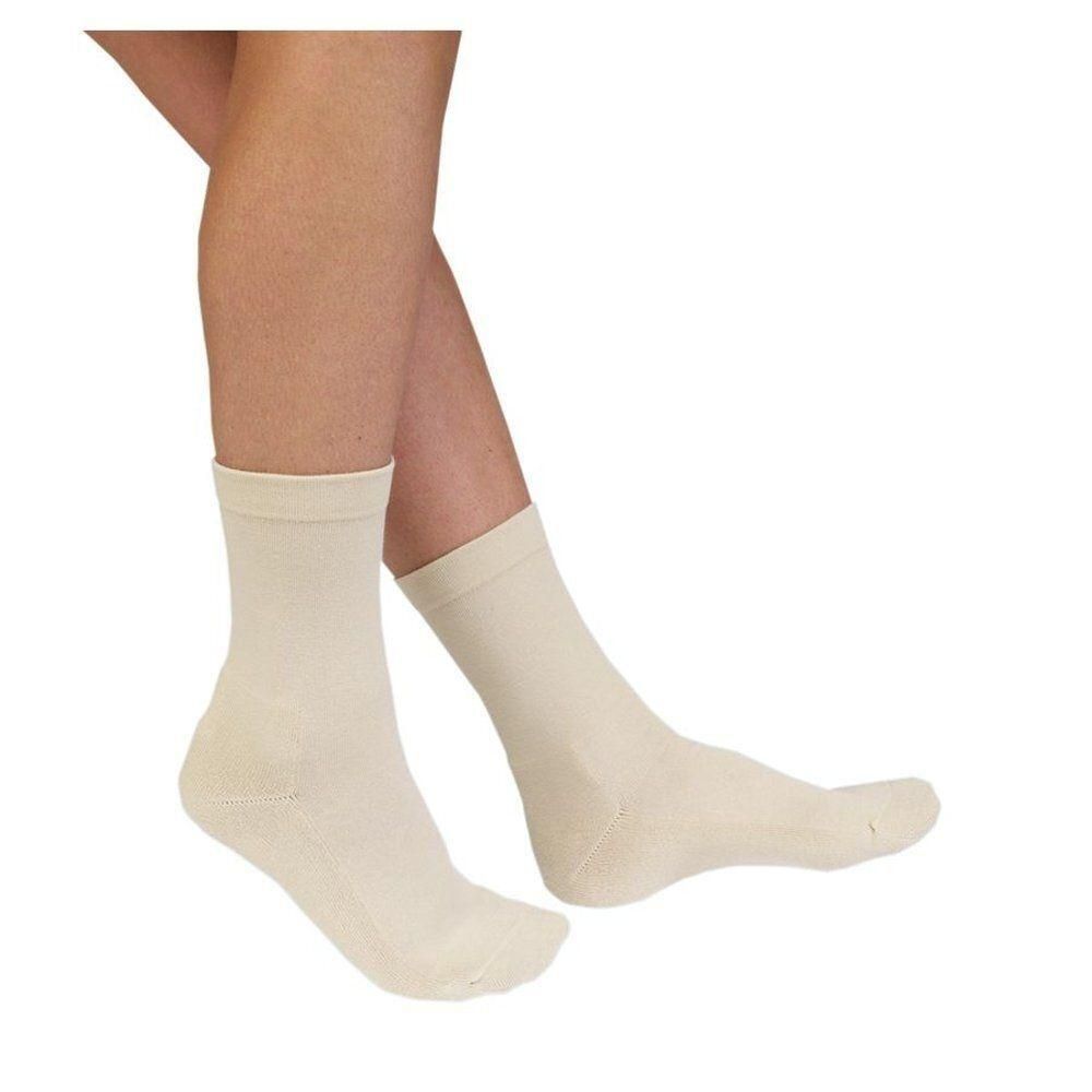 Deux chaussettes couleur crème en tissu éponge, portées sur des jambes humaines.