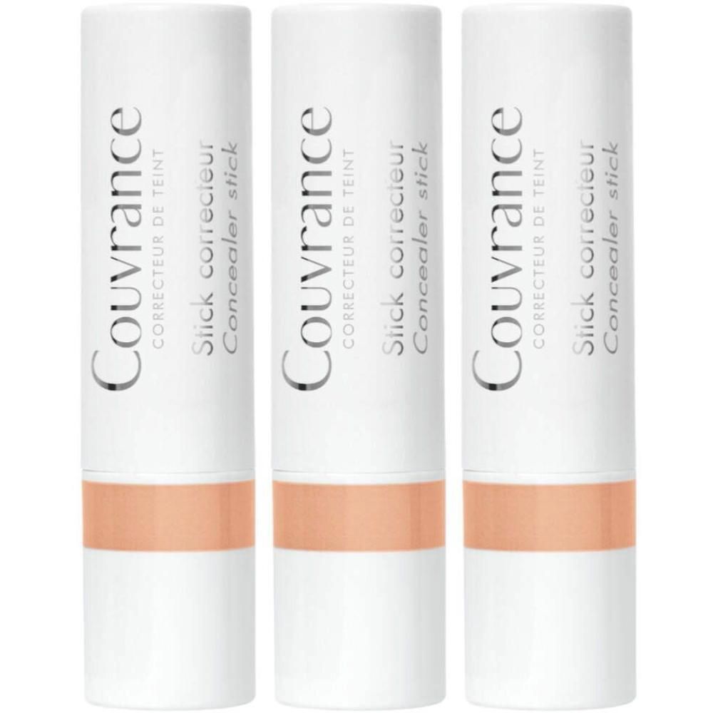 Drie witte concealer sticks, koraalkleur. Opschrift: Couvrance, Correcteur de teint, Slick correcteur, Concealer stick.