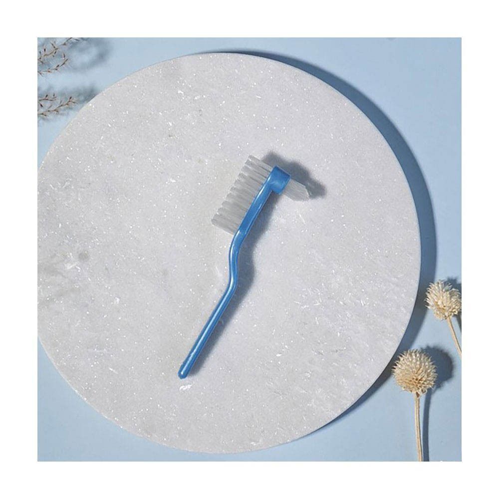 Brosse pour prothèses dentaires Jordan Clinic avec manche bleu et double tête de poils sur surface blanche.