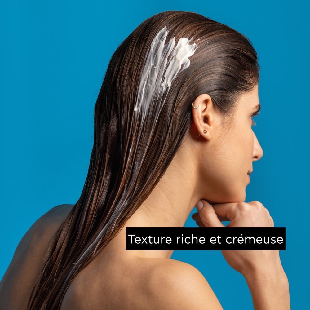 Femme avec un masque capillaire riche et crémeux appliqué sur ses cheveux.