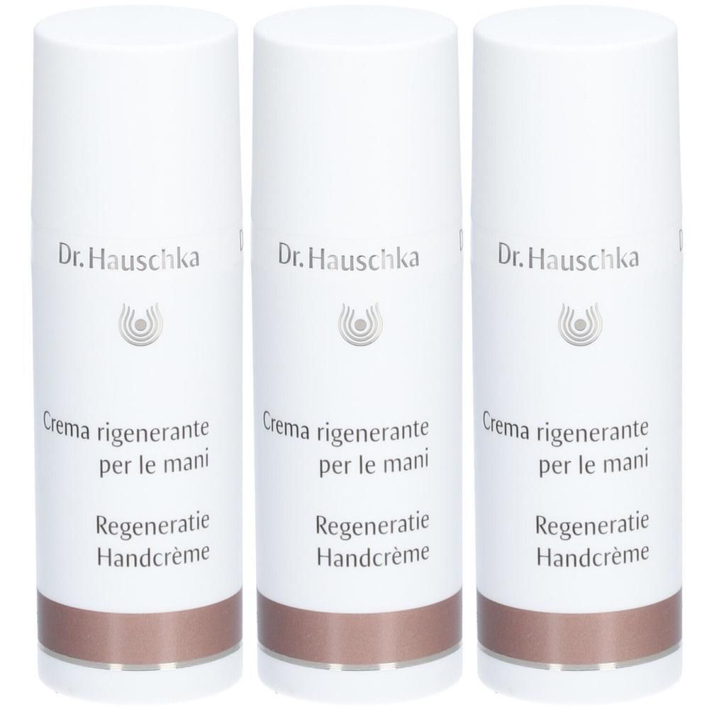 Drie witte flacons Dr. Hauschka handcrème met koperkleurige band.