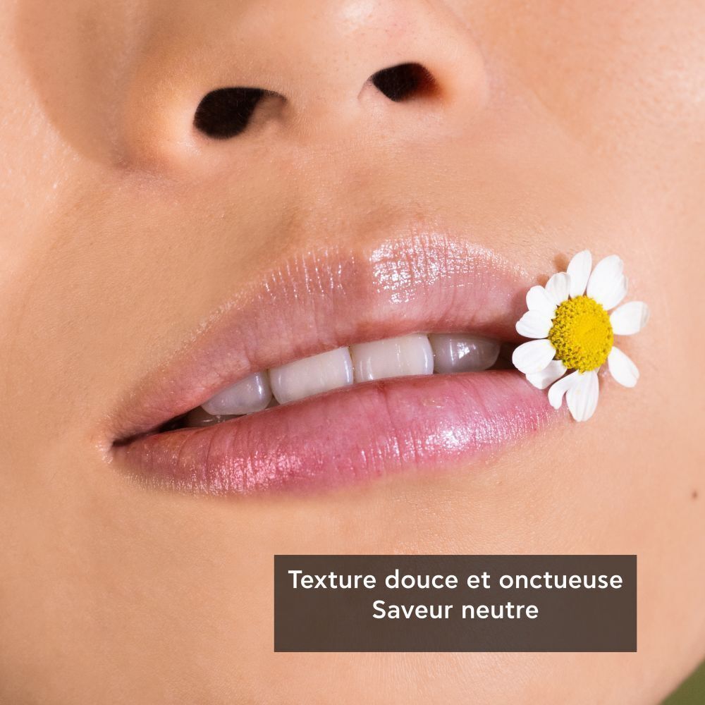 Gros plan sur des lèvres avec un baume à lèvres et une fleur de camomille. Texture douce et onctueuse, saveur neutre.