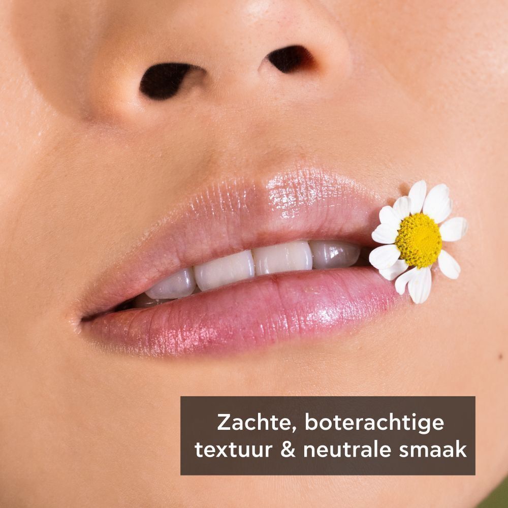 Close-up van lippen met een lippenbalsem en een kamillebloem. Zachte, boterachtige textuur, neutrale smaak.