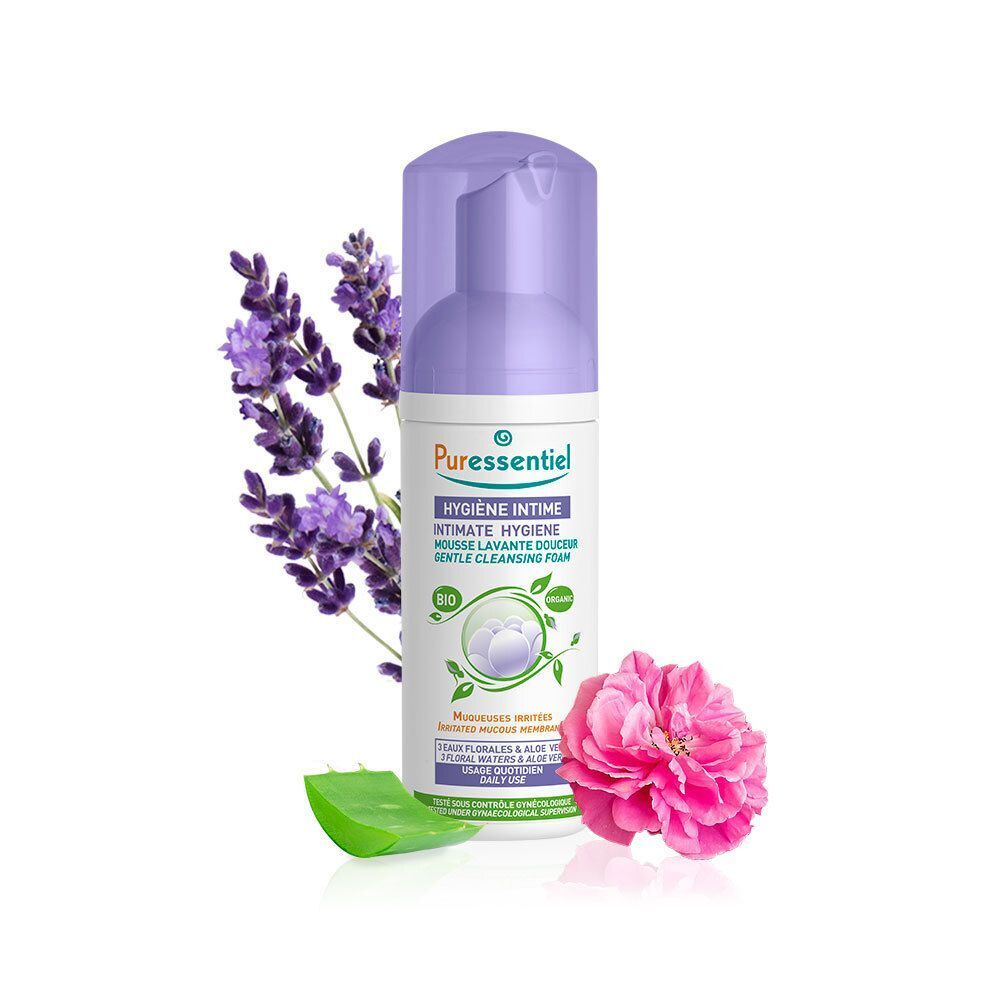 Een flacon Puressentiel Intieme Hygiëne zachte wasschuim naast lavendel, roos en aloë vera.