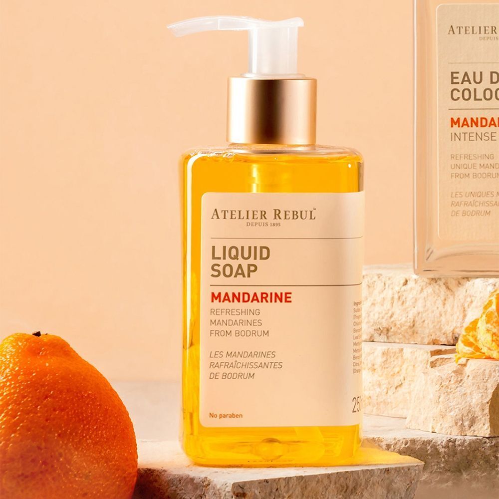 Un flacon de savon liquide Atelier Rebul "Mandarine" avec distributeur à pompe, entouré de mandarines.