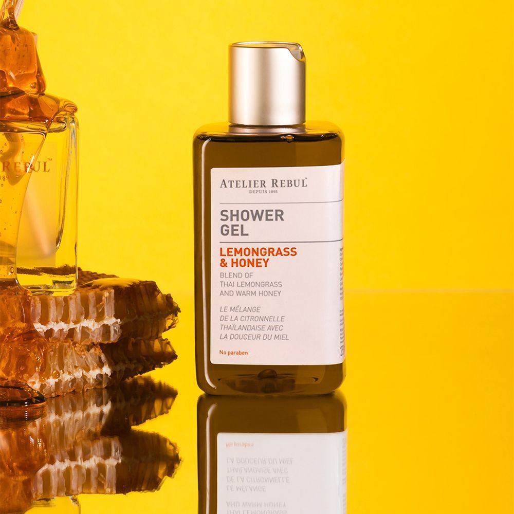 Bouteille de gel douche Atelier Rebul Lemongrass & Honey à côté d'une décoration en nid d'abeille.