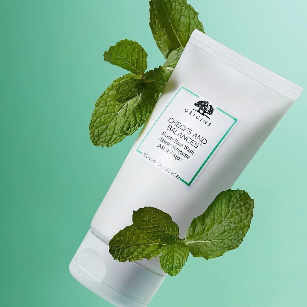 Tube de nettoyant visage moussant ORIGINS Checks and Balances™ avec des feuilles de menthe.