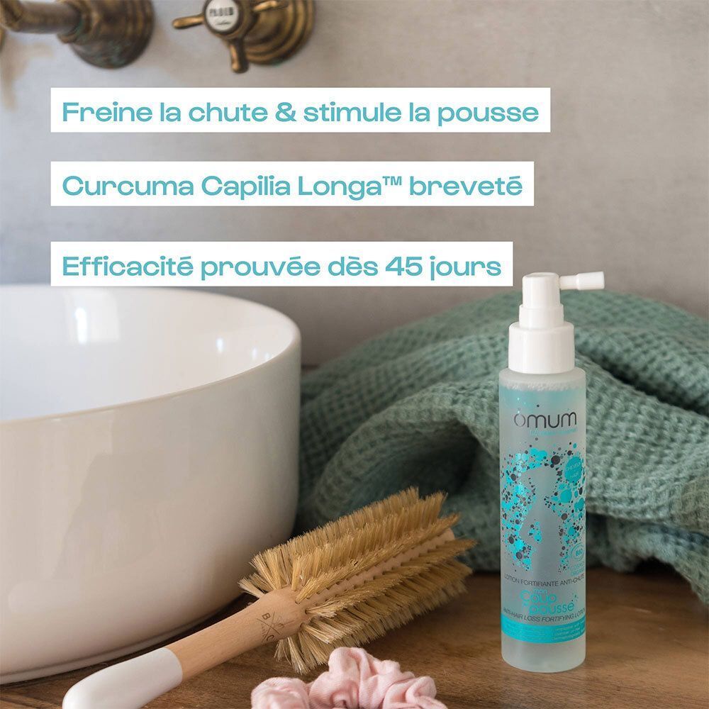 Lotion Fortifiante Anti-Chute Bio Omum à côté d'une brosse et d'un lavabo.