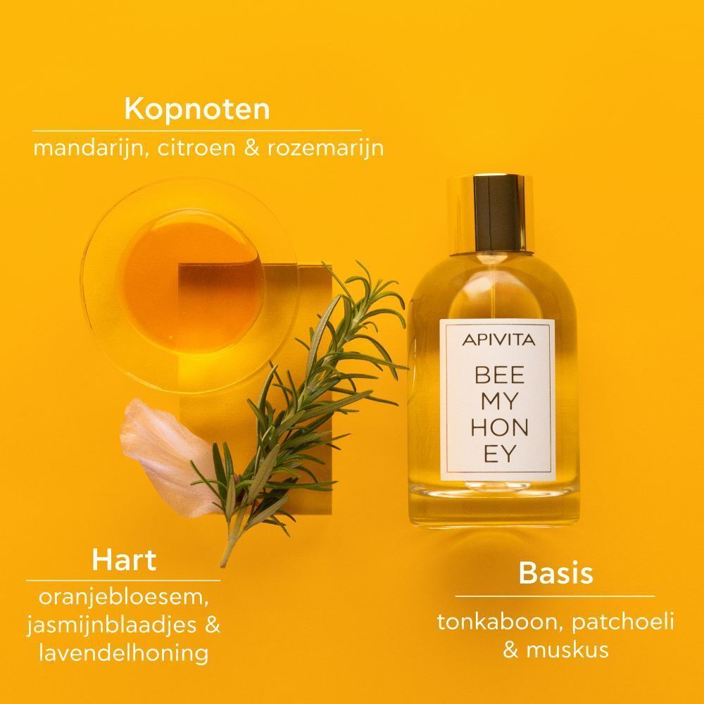Apivita Bee My Honey Eau de Toilette flesje naast een kom met vloeistof, een takje rozemarijn en bloemblaadjes.