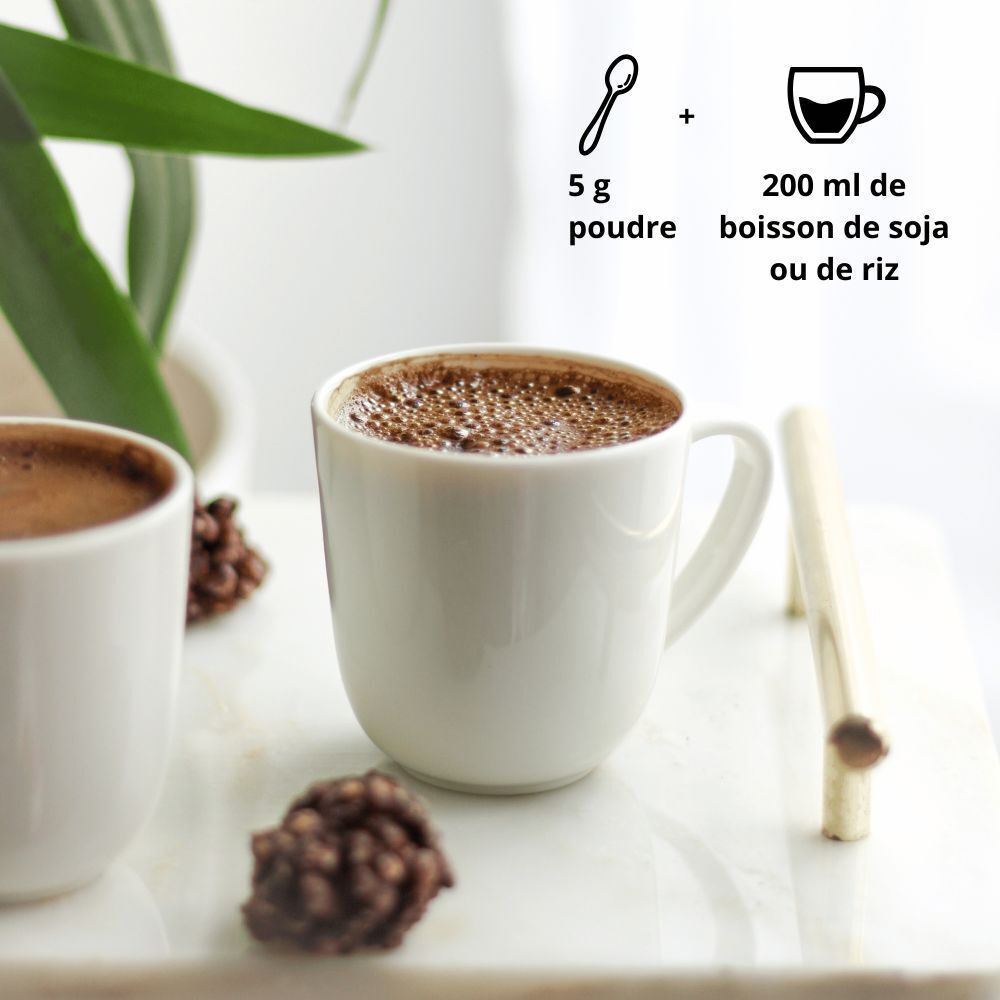 Une tasse de Purasana Cacao-Maca Latté préparé à côté d'un pot de poudre.