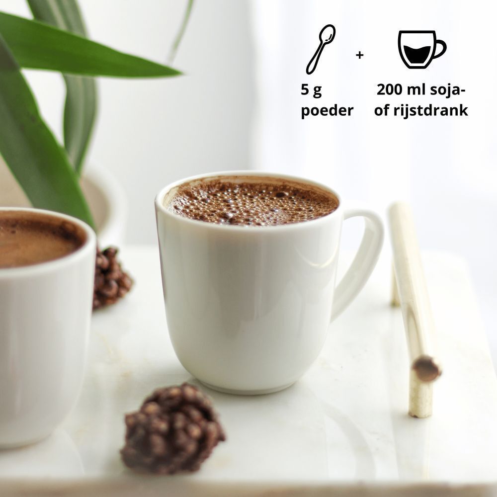Kopje bereide Purasana Cacao-Maca Latté naast een pot met poeder.
