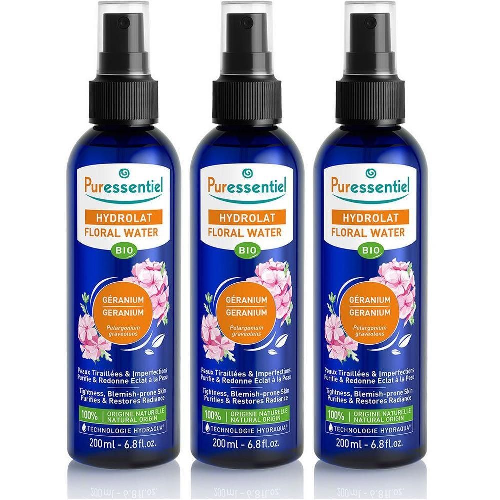 Drie flacons Puressentiel Hydrolat de Géranium Bio met spraykop. Blauwe flacons met oranje etiket en bloemenmotief.