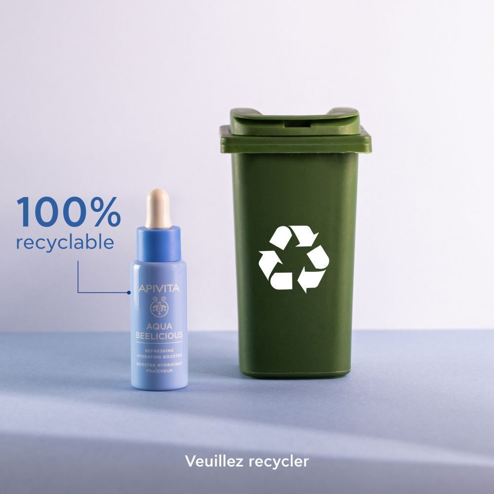 Un flacon de l'Apivita Aqua Beelicious Booster à côté d'une poubelle de recyclage verte, 100% recyclable.