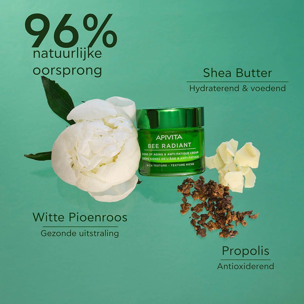 Een groen potje Apivita Bee Radiant crème omringd door witte bloemen, shea butter en propolis.