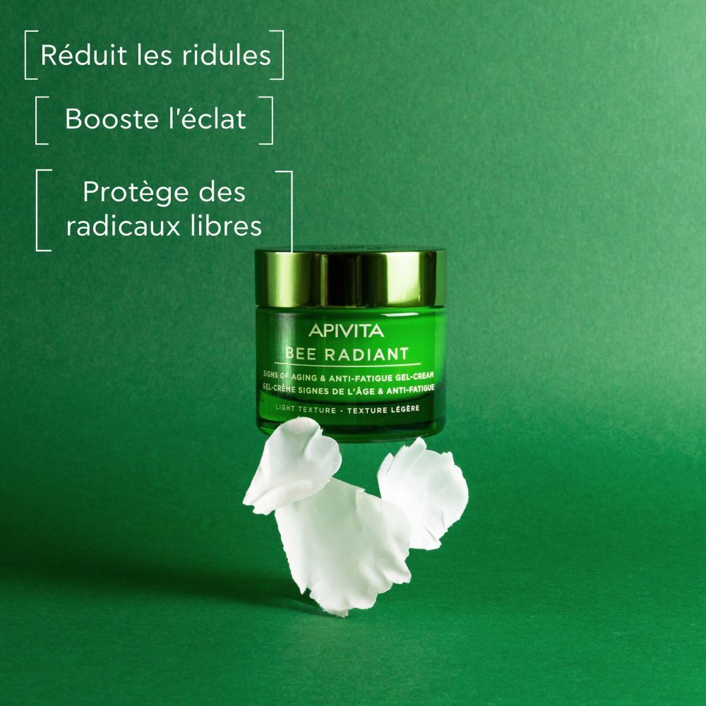 Pot vert Apivita Bee Radiant avec pétales blancs et indications textuelles.