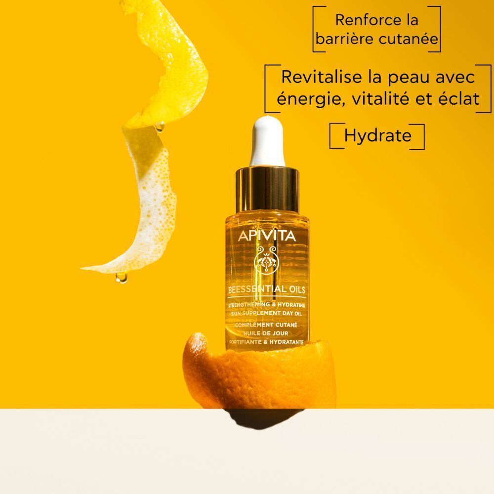 Flacon Apivita Beessential Oils sur une peau d'orange, entouré de zestes d'agrumes et de gouttes d'eau.