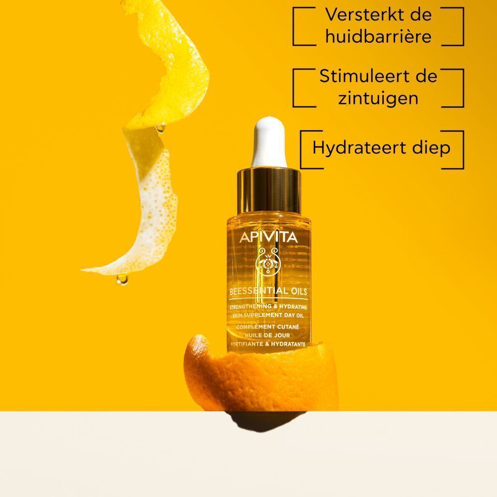 Flesje Apivita Beessential Oils op een sinaasappelschil, omringd door citruszest en waterdruppels.