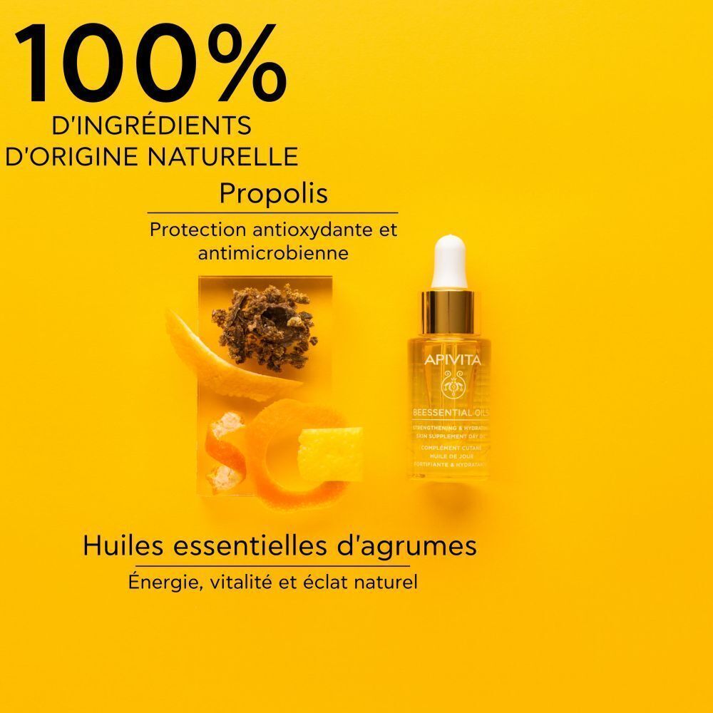 Flacon Apivita Beessential Oils à côté de granulés de propolis et de zestes d'agrumes sur fond jaune.