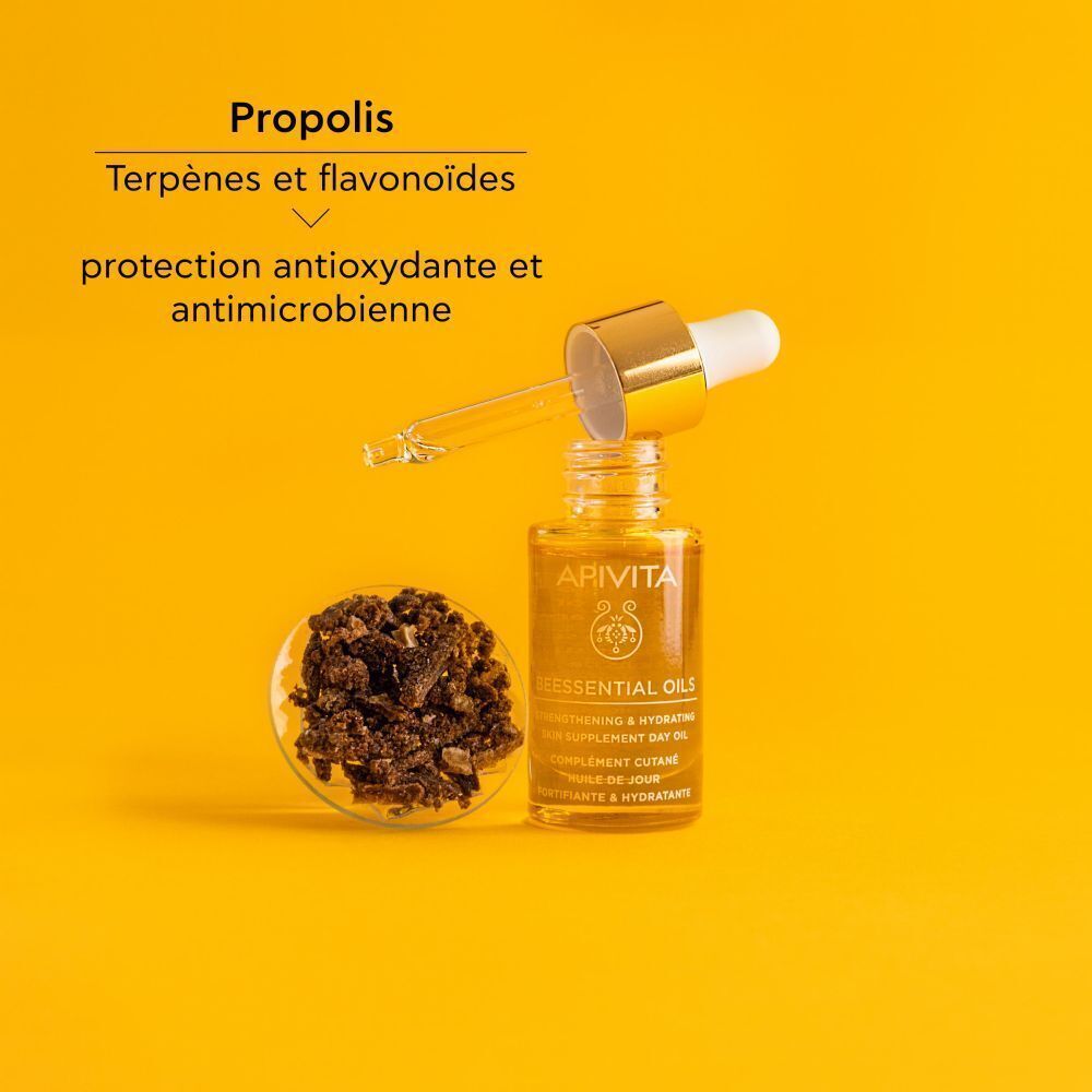 Flacon Apivita Beessential Oils avec pipette, à côté d'un bol de granulés de propolis.
